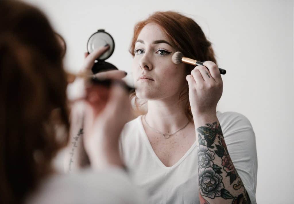Picture of a woman applying makeup to her face